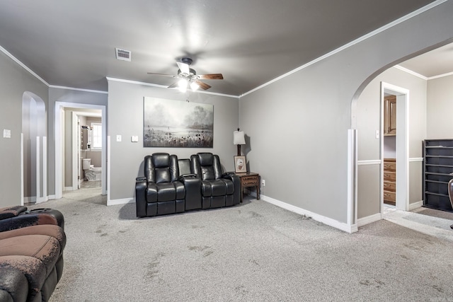 cinema room with ceiling fan, crown molding, and light carpet