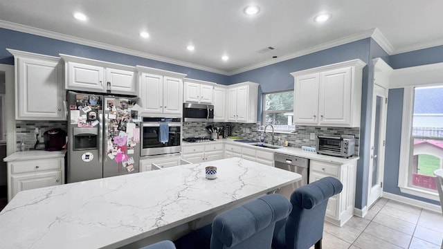 kitchen featuring sink, light tile patterned floors, appliances with stainless steel finishes, a kitchen bar, and white cabinetry