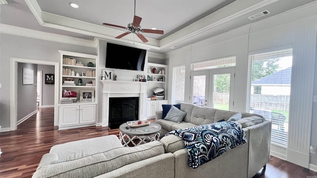 living room featuring dark hardwood / wood-style floors, a raised ceiling, ceiling fan, and ornamental molding