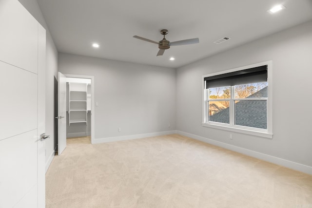 unfurnished bedroom featuring ceiling fan, light colored carpet, a spacious closet, and a closet