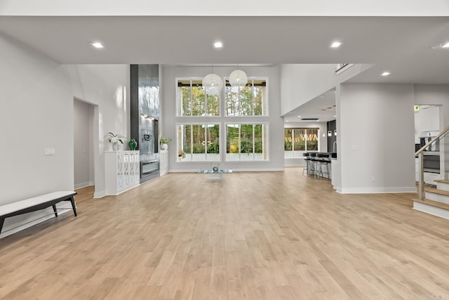 unfurnished living room with a towering ceiling and light hardwood / wood-style flooring