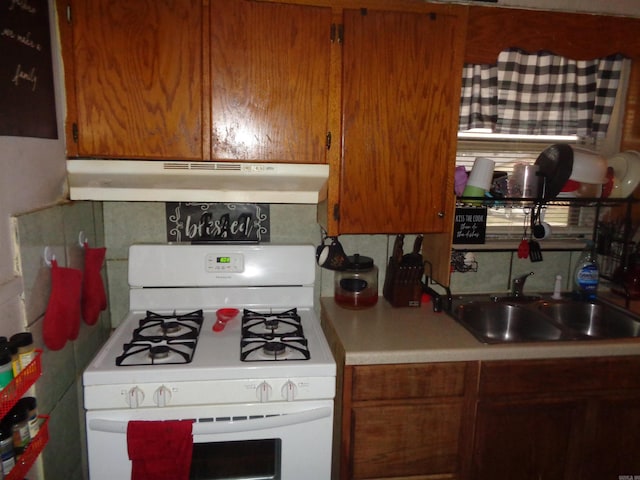 kitchen with decorative backsplash, white range with gas stovetop, and sink