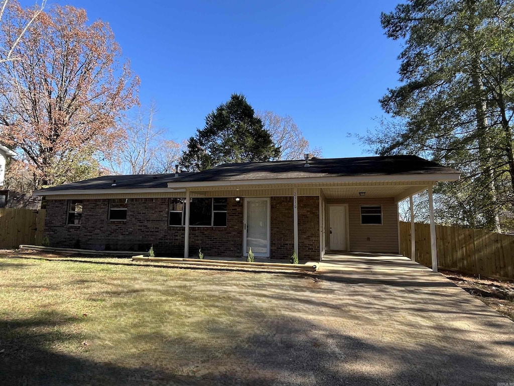 back of property with a carport and a lawn