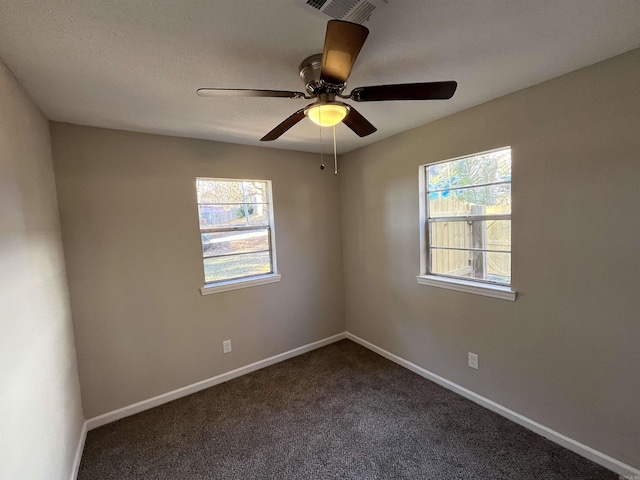 carpeted spare room featuring ceiling fan and a healthy amount of sunlight