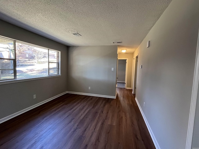 spare room with a textured ceiling and dark hardwood / wood-style floors