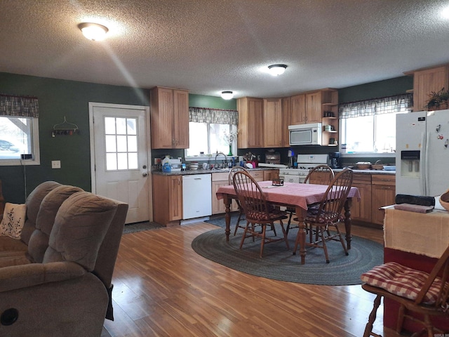 kitchen featuring a textured ceiling, sink, wood-type flooring, and white appliances