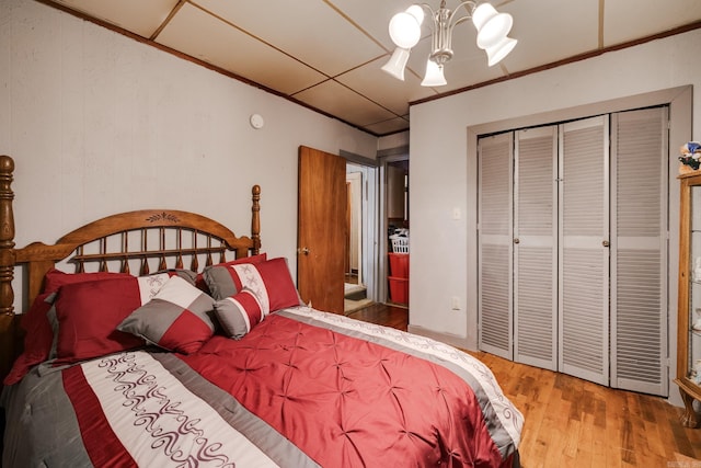 bedroom featuring wood-type flooring, an inviting chandelier, and a closet