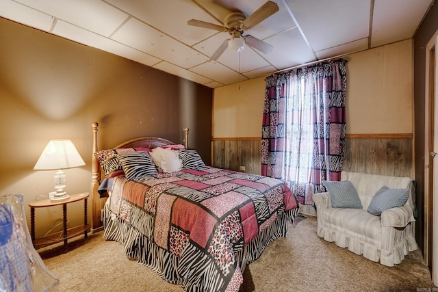 carpeted bedroom featuring multiple windows, ceiling fan, and wooden walls