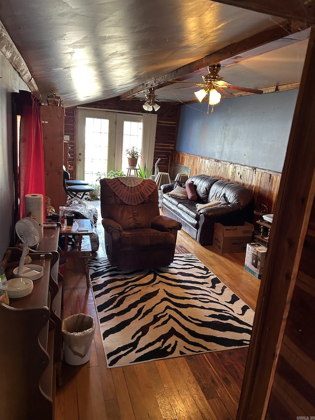 living room with wooden walls, hardwood / wood-style floors, ceiling fan, and french doors