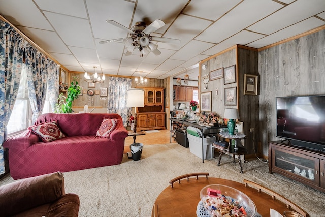 carpeted living room featuring ceiling fan with notable chandelier, a healthy amount of sunlight, and wood walls