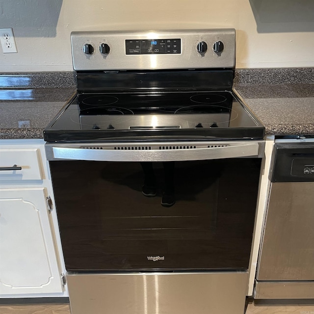 kitchen with stainless steel electric range and white cabinetry