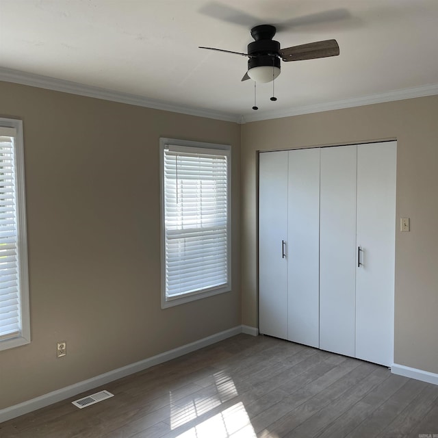 unfurnished bedroom with ceiling fan, ornamental molding, and a closet