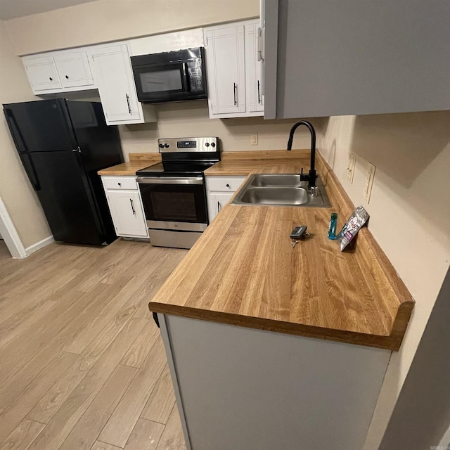 kitchen featuring black appliances, white cabinets, sink, light wood-type flooring, and butcher block countertops