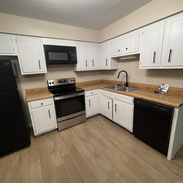 kitchen with sink, black appliances, butcher block countertops, white cabinets, and light hardwood / wood-style floors