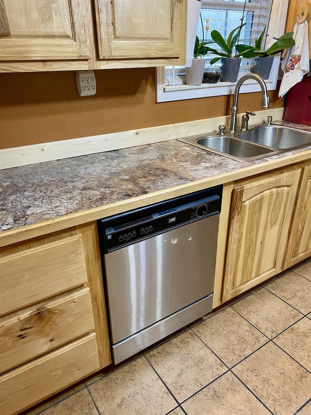 kitchen with stainless steel dishwasher, light tile patterned floors, sink, and light brown cabinetry