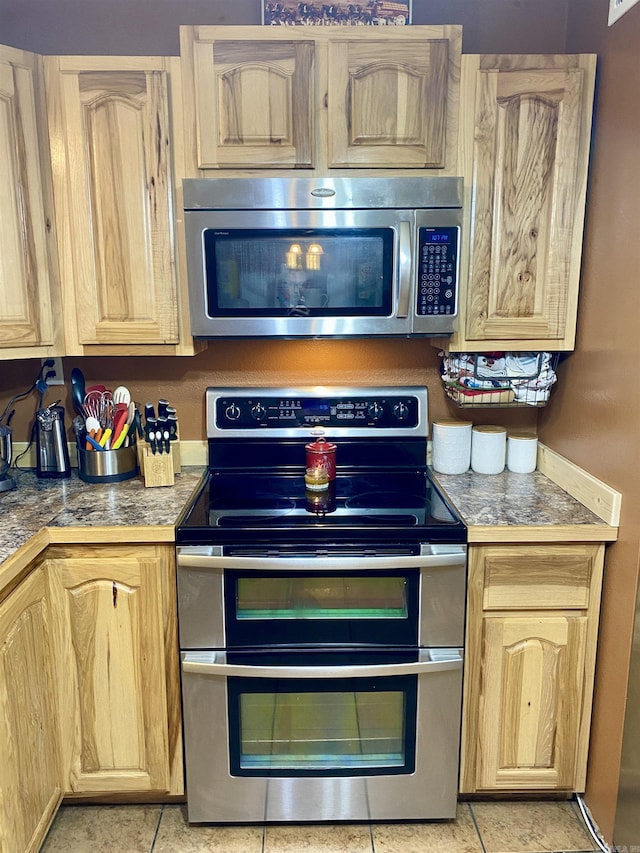 kitchen with light brown cabinetry, light tile patterned flooring, and stainless steel appliances