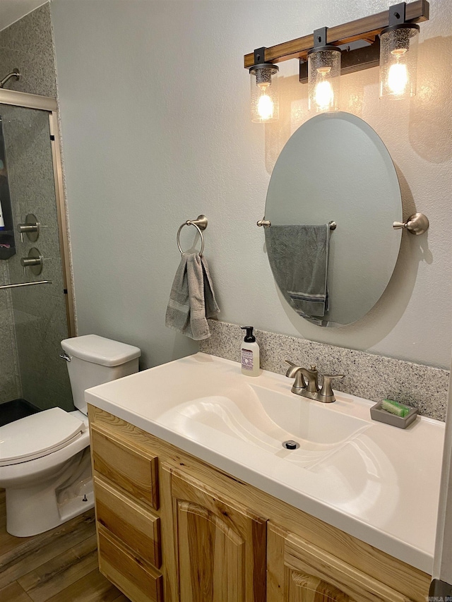 bathroom featuring hardwood / wood-style floors, vanity, toilet, and a shower with door