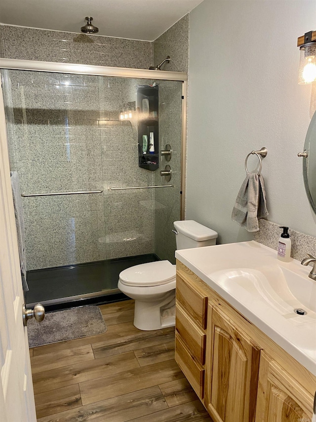 bathroom with hardwood / wood-style floors, vanity, a shower with door, and toilet