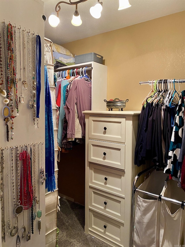 walk in closet featuring dark carpet