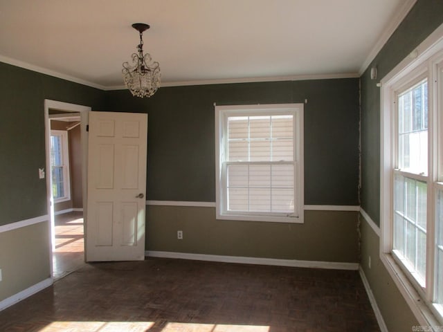 spare room featuring dark parquet flooring, crown molding, and a chandelier