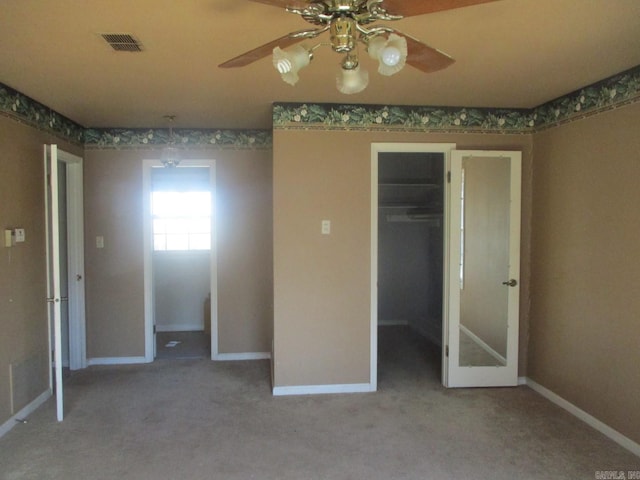 unfurnished bedroom with carpet floors, a spacious closet, a closet, and ceiling fan