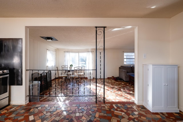 interior space with plenty of natural light, stainless steel range oven, and a textured ceiling