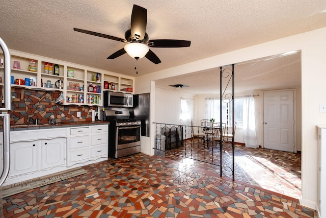 kitchen featuring white cabinets, ceiling fan, stainless steel appliances, and a textured ceiling