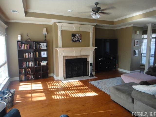 living room with a tile fireplace, a wealth of natural light, and crown molding