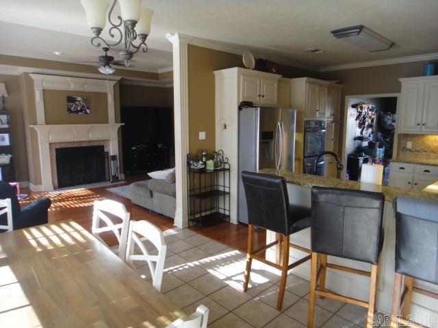 kitchen featuring double oven, crown molding, sink, light tile patterned floors, and a tiled fireplace