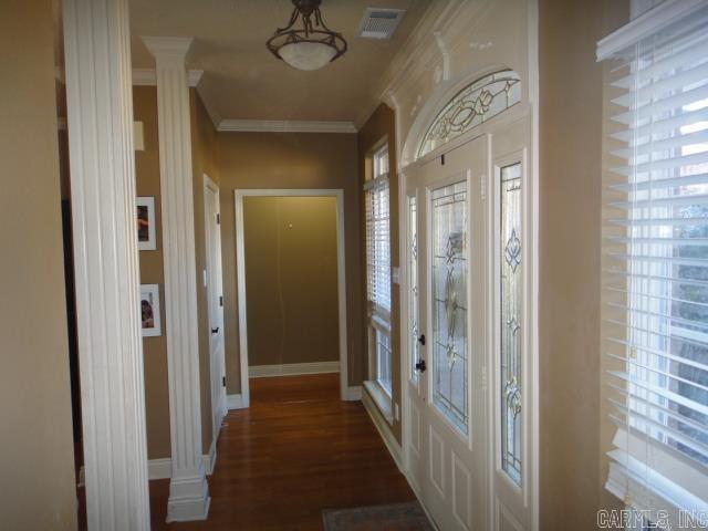 hall with decorative columns, crown molding, and dark hardwood / wood-style floors