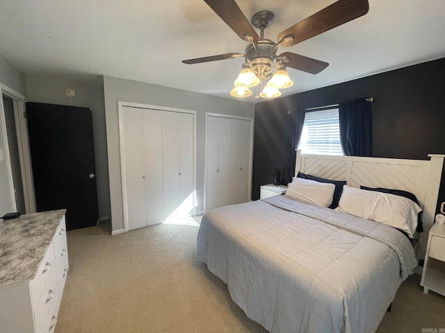 bedroom with multiple closets, ceiling fan, and light colored carpet