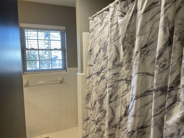 bathroom with a shower with shower curtain and tile walls