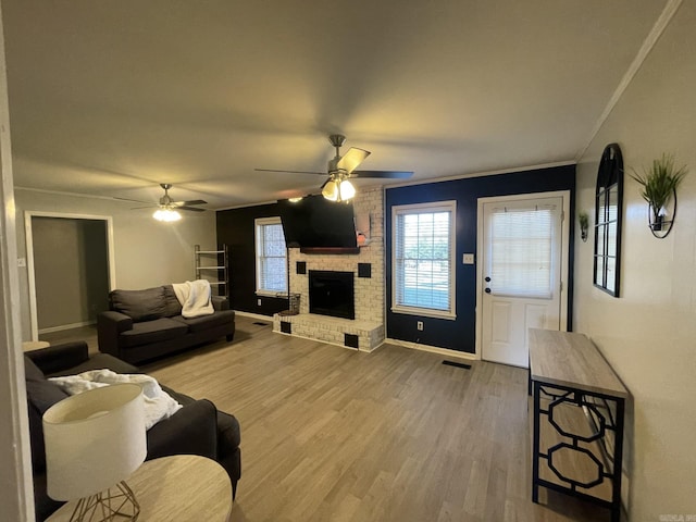 living room with hardwood / wood-style flooring, ceiling fan, ornamental molding, and a fireplace