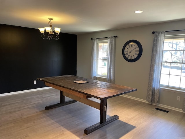 unfurnished dining area with hardwood / wood-style floors and an inviting chandelier