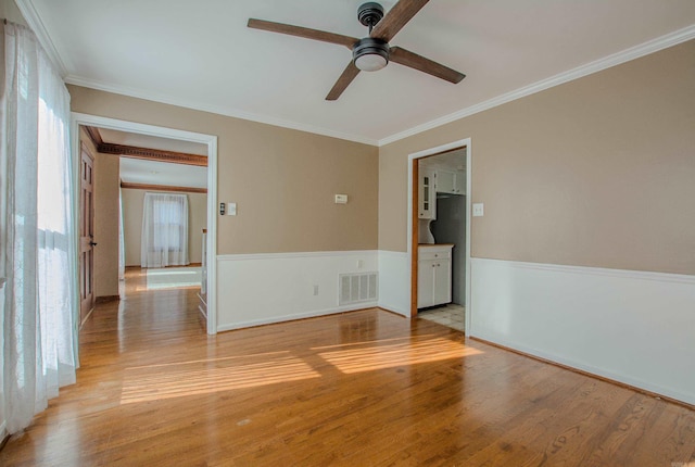 spare room featuring ceiling fan, light wood-type flooring, and ornamental molding