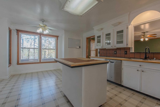 kitchen with tasteful backsplash, stainless steel dishwasher, sink, white cabinetry, and a kitchen island