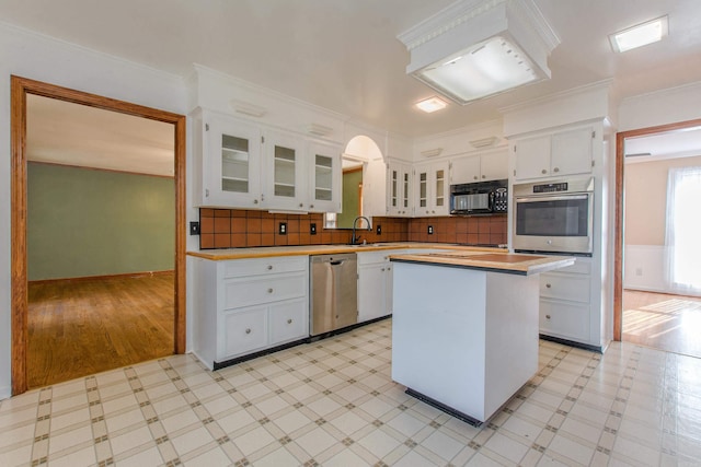 kitchen featuring pendant lighting, a center island, white cabinets, decorative backsplash, and appliances with stainless steel finishes