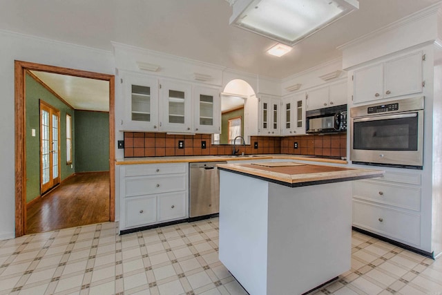 kitchen featuring ornamental molding, stainless steel appliances, sink, white cabinets, and a kitchen island