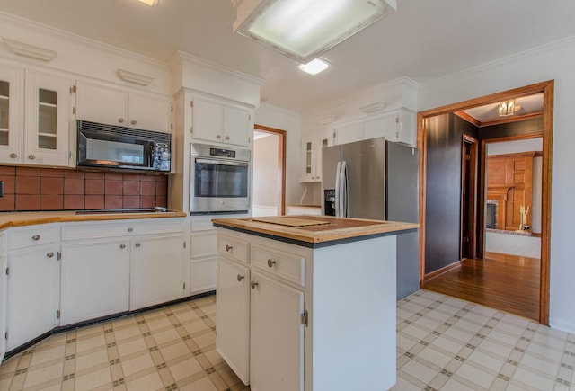 kitchen featuring white cabinetry, a center island, stainless steel appliances, and ornamental molding