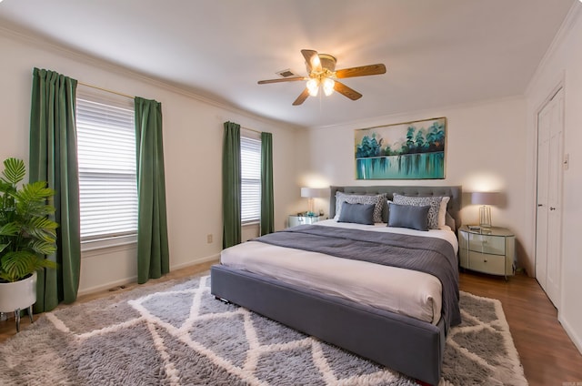 bedroom featuring ceiling fan, wood-type flooring, crown molding, and multiple windows