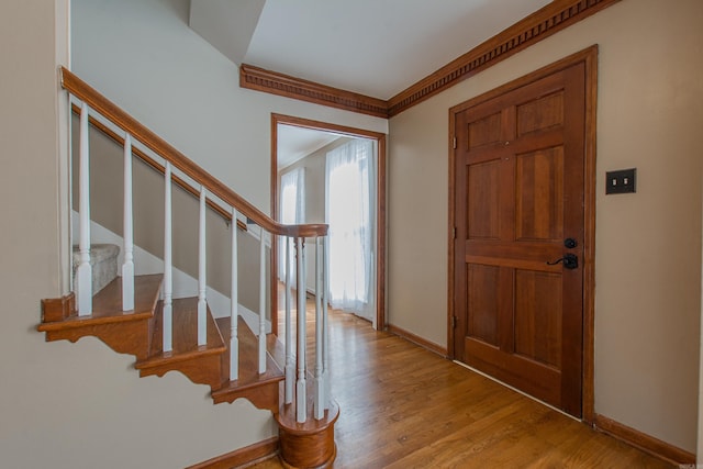 foyer entrance with crown molding and light wood-type flooring