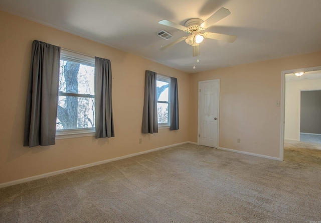 carpeted empty room with ceiling fan and plenty of natural light