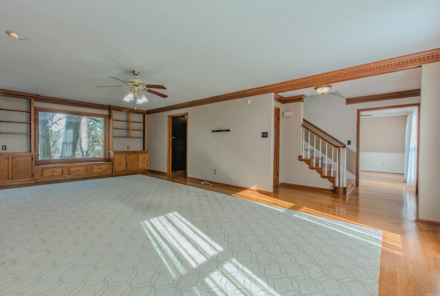 unfurnished living room featuring ceiling fan, ornamental molding, and built in shelves