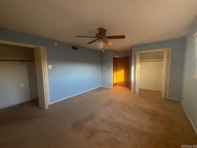 unfurnished bedroom featuring a textured ceiling, ceiling fan, and light carpet