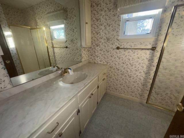 bathroom with tile patterned floors, vanity, a healthy amount of sunlight, and walk in shower