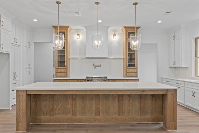 kitchen featuring pendant lighting, a spacious island, white cabinetry, and light wood-type flooring