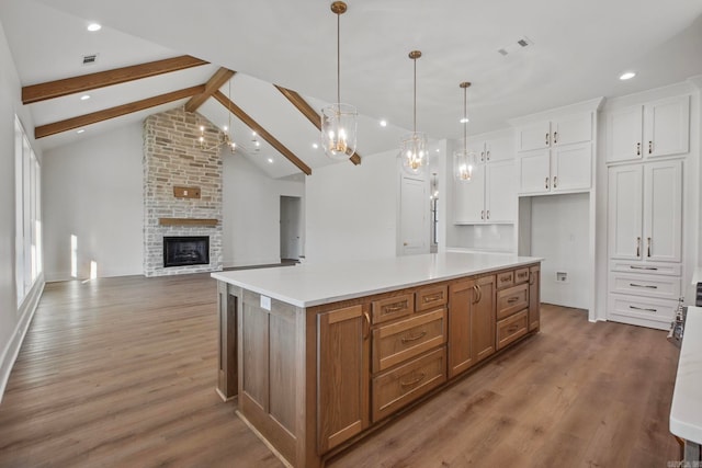 kitchen with beam ceiling, white cabinetry, a large island, hanging light fixtures, and a fireplace