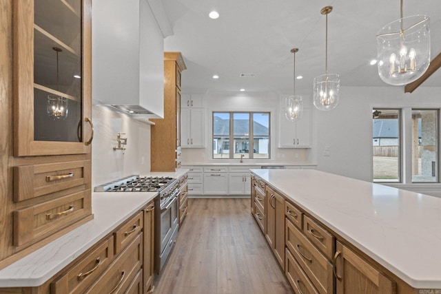 kitchen featuring a center island, double oven range, decorative light fixtures, white cabinets, and light wood-type flooring