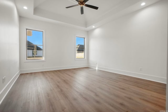 empty room featuring hardwood / wood-style floors, ceiling fan, and a tray ceiling