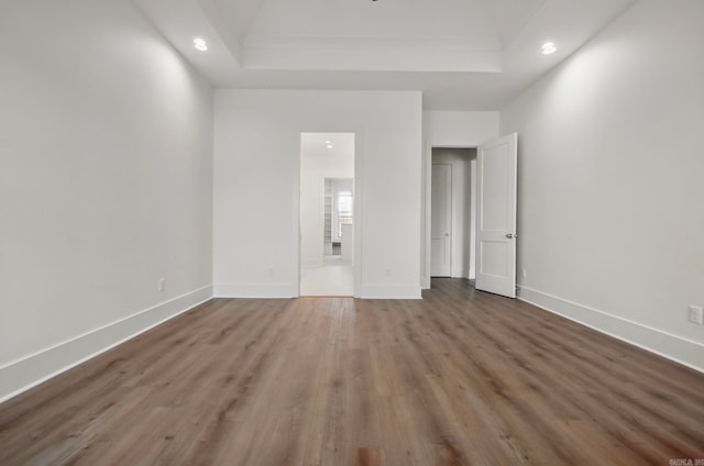 unfurnished bedroom featuring a tray ceiling and wood-type flooring